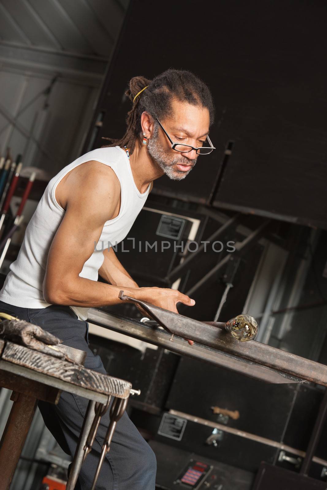 Busy African man working with fine art glass object in factory