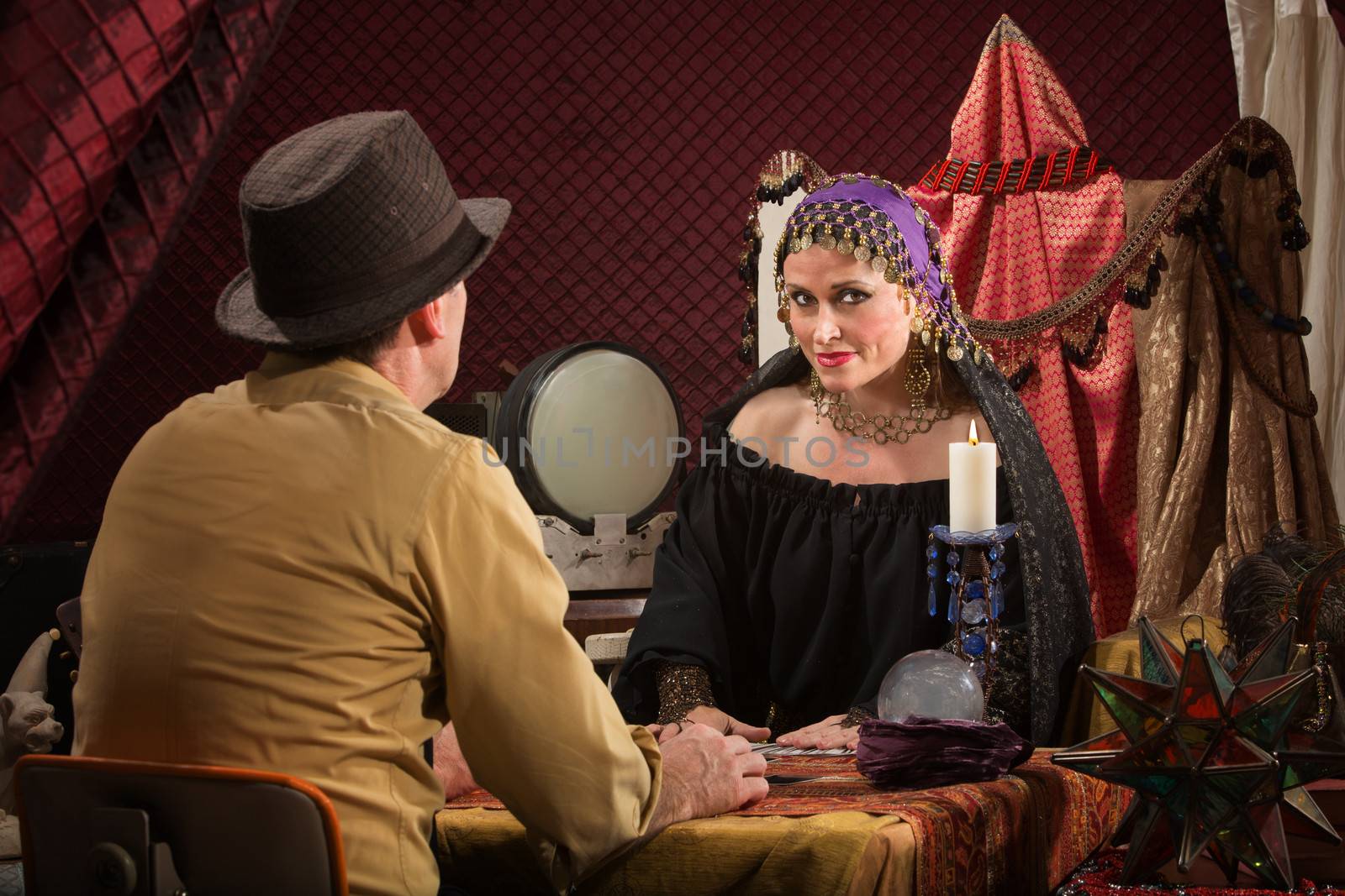 Smiling beautiful fortune teller with crystal ball and customer