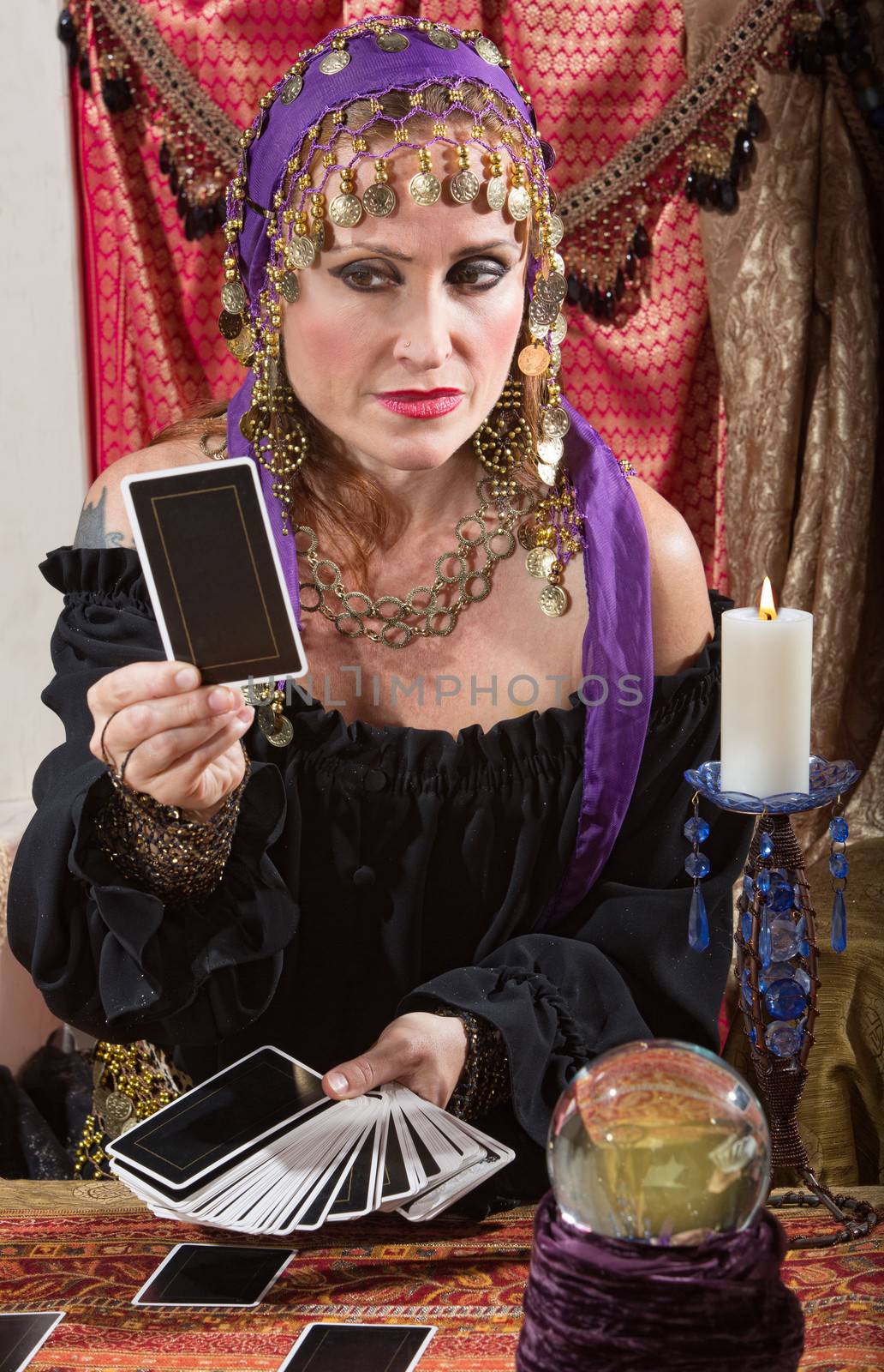 Stoic Roma lady looking at a tarot card indoors