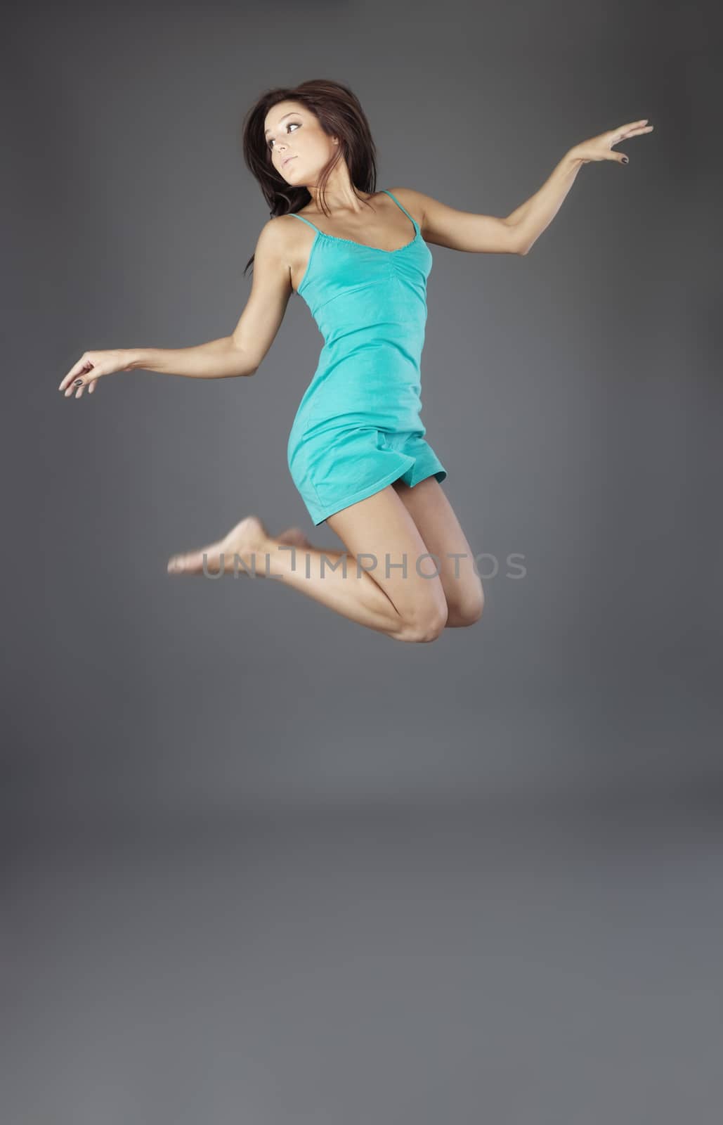 Elegant lady jumping on a gray background