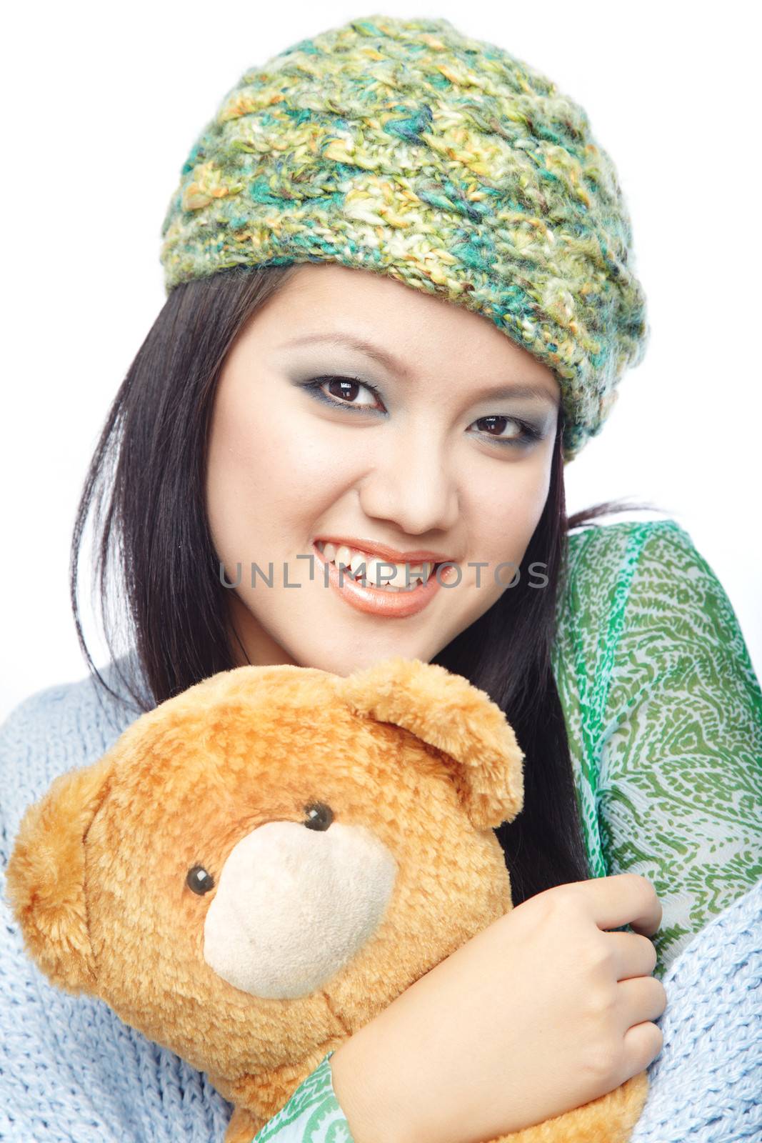 Smiling brunnete in the winter clothes and cap holding Teddy bear