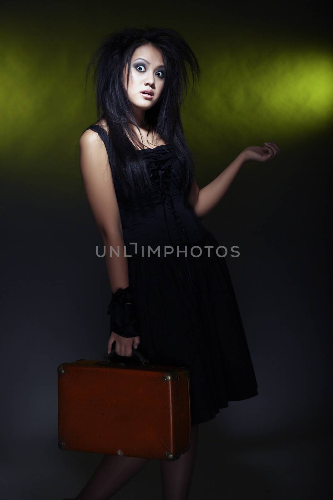 Crazy woman holding case on a dark green background. Artistic darkness and colors added