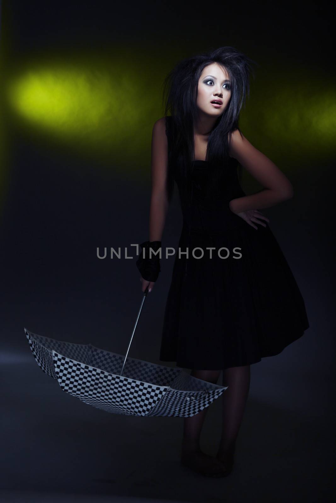 Brunette lady holding umbrella on a dark background. Artistic darkness and colors added
