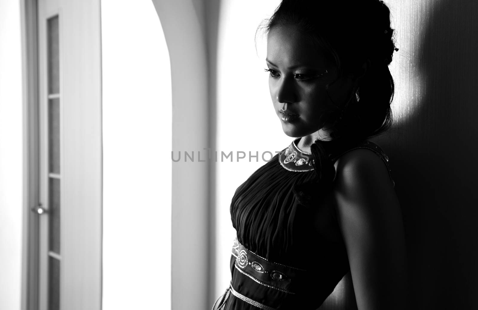 Elegant brunette lady indoors. Monochrome photo with shadows and darkness