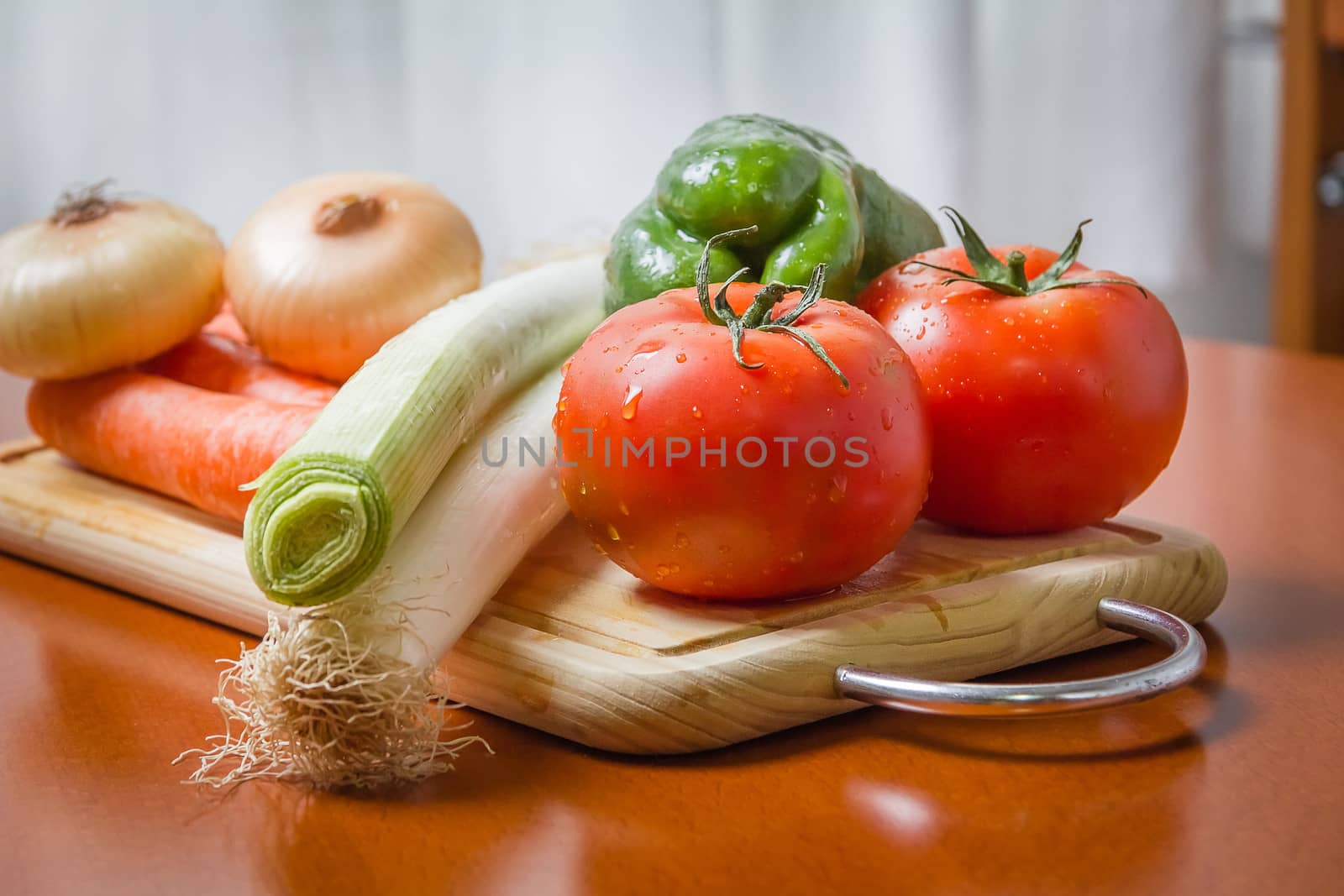 Fresh vegetables on cutting board in a wooden kitchen table