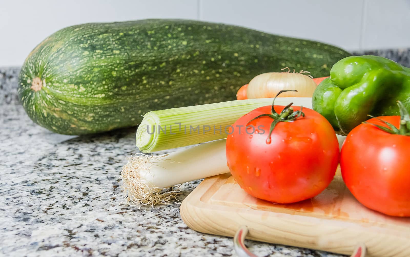 Fresh vegetables on cutting board in the kitchen over granite worktop