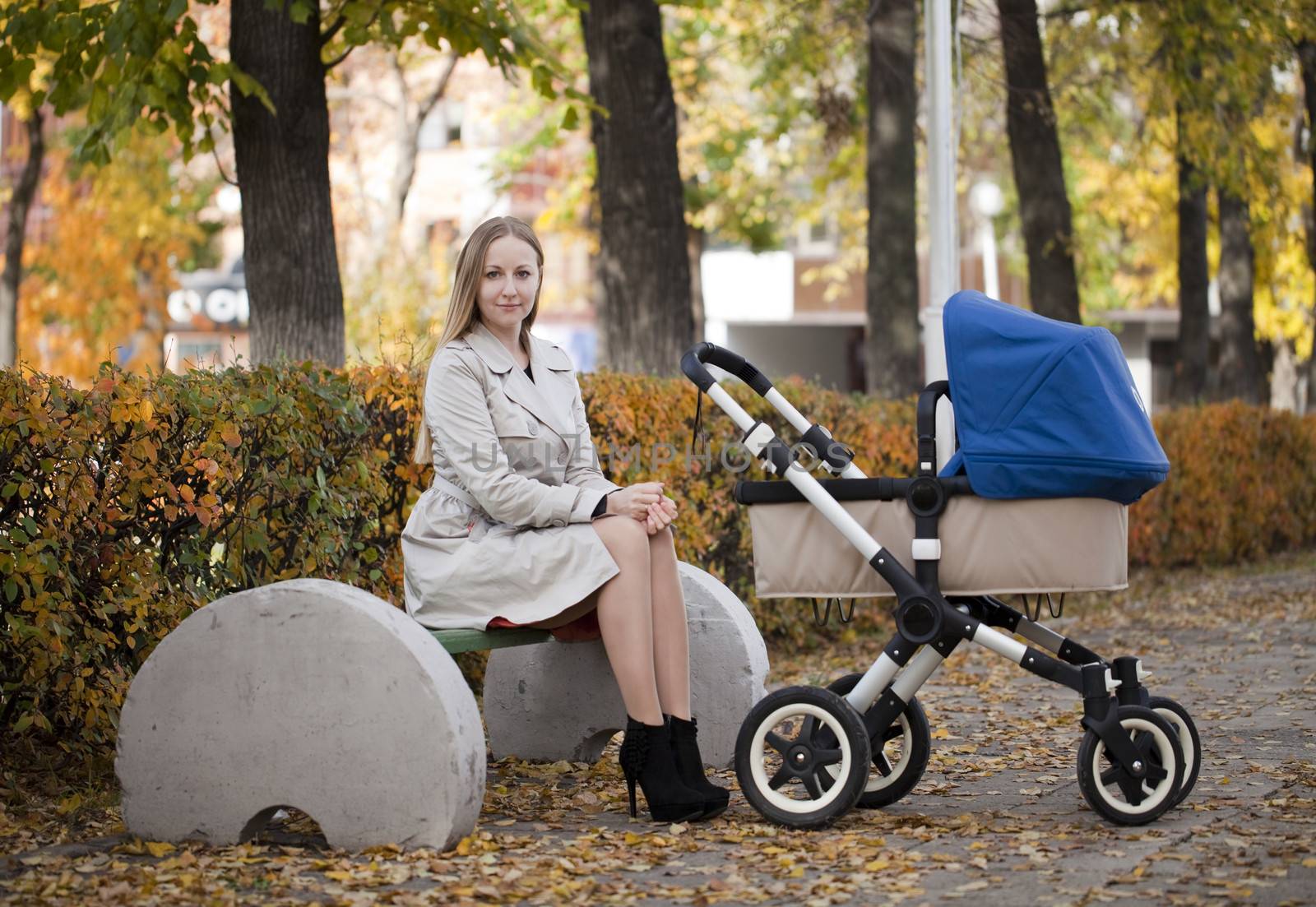 Mother with baby stroller for a newborn in autumn park