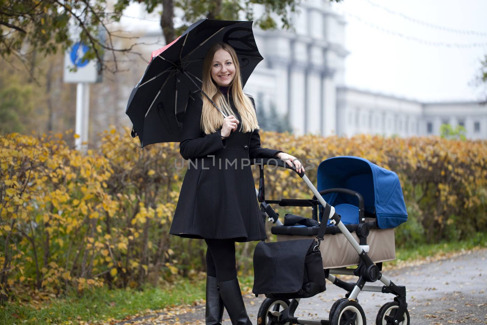 Mother with baby stroller for a newborn in autumn park