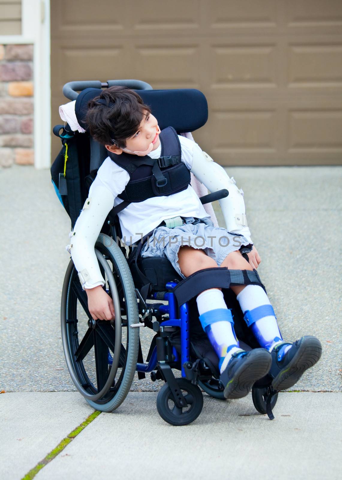 Seven year old biracial disabled boy in wheelchair. Child has cerebral palsy.