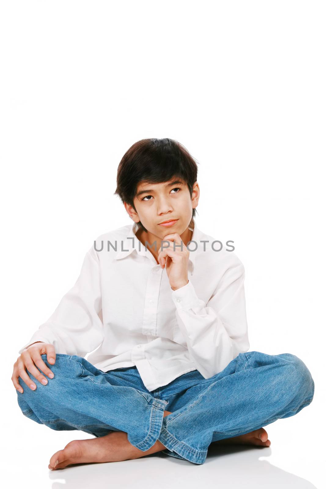 Twelve year old boy sitting, thinking with chin on hand