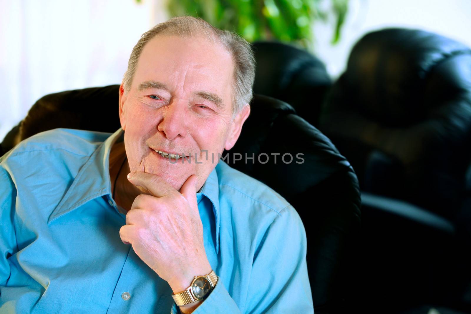 Happy Elderly man in eighties laughing in leather recliner