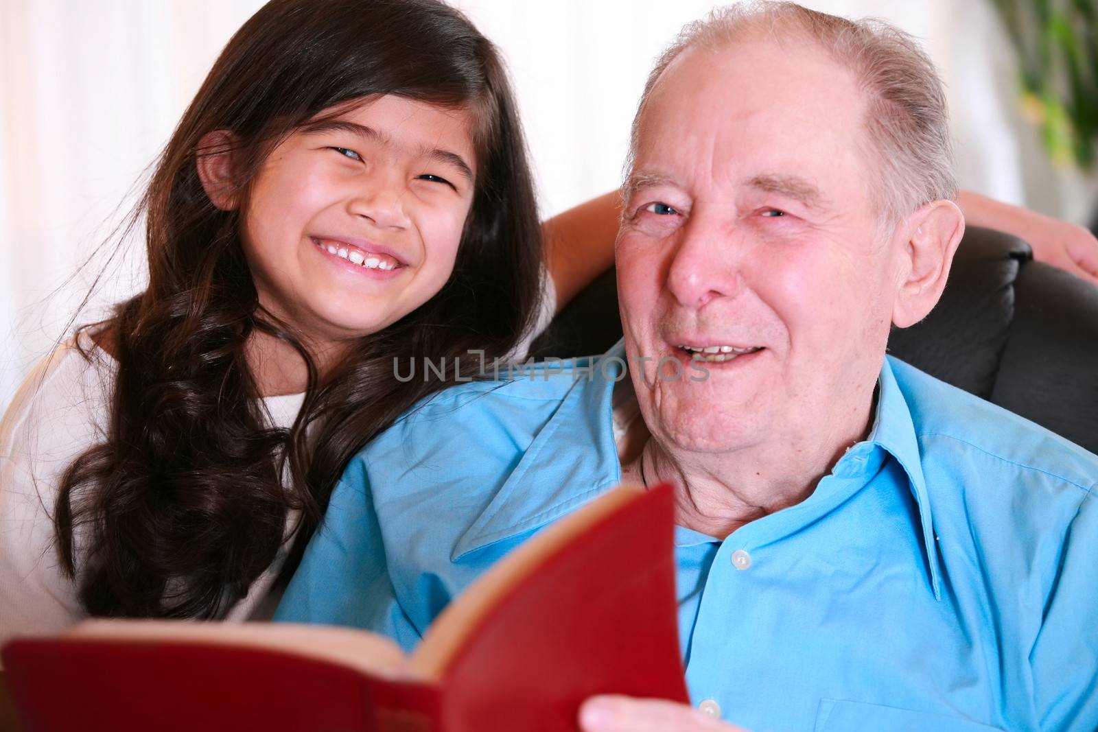 Elderly man and little girl reading Bible together by jarenwicklund