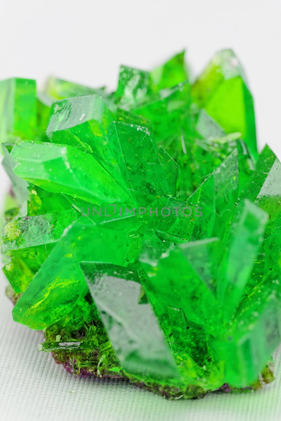 Close up picture about a crystal with emerald color on white background (green crystal)