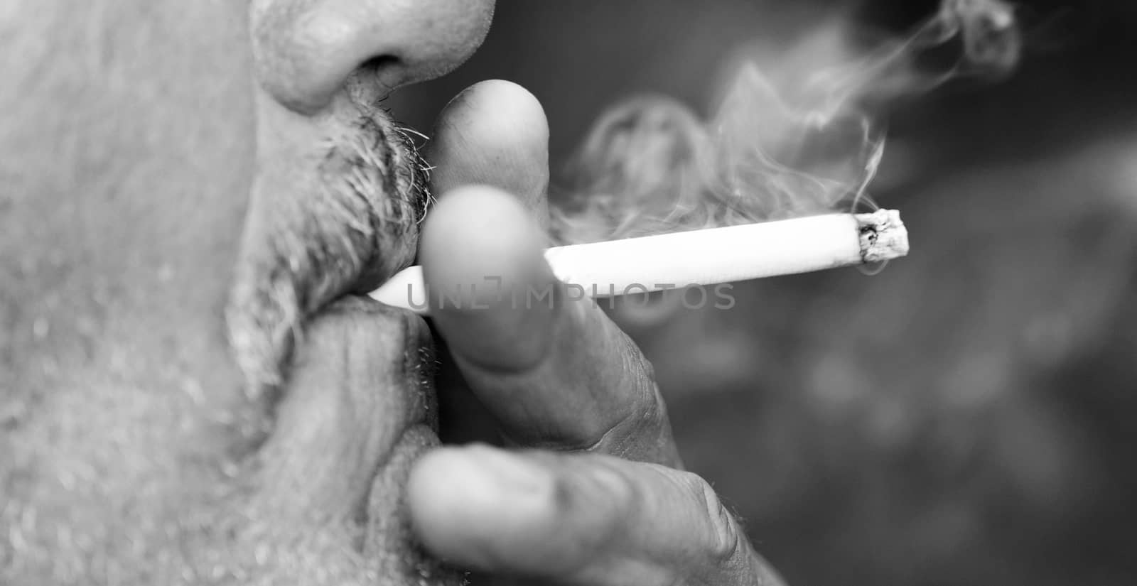 Man smoking a cigarette against a black background (black and white)