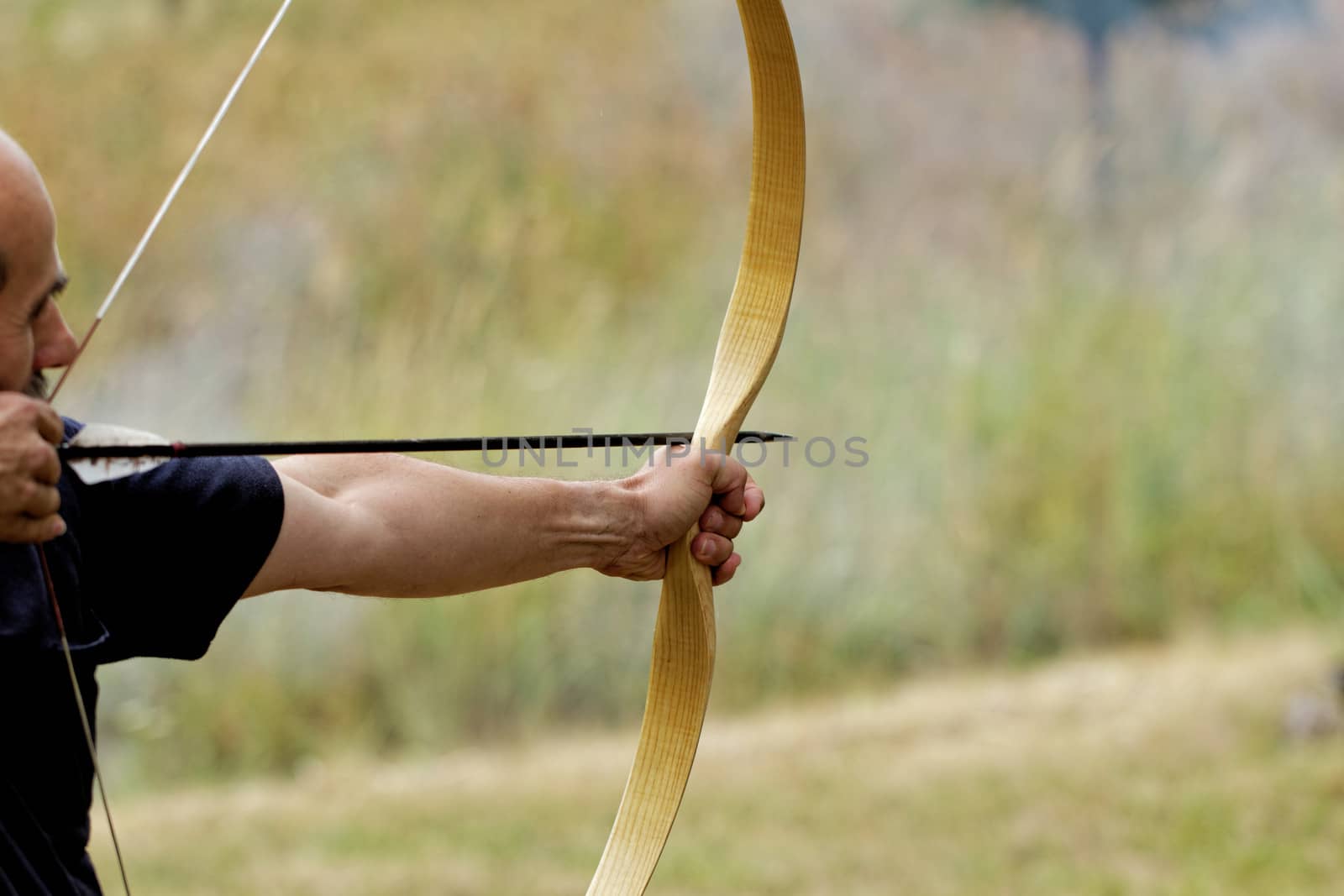 archery man shooting arrow with bow in the nature