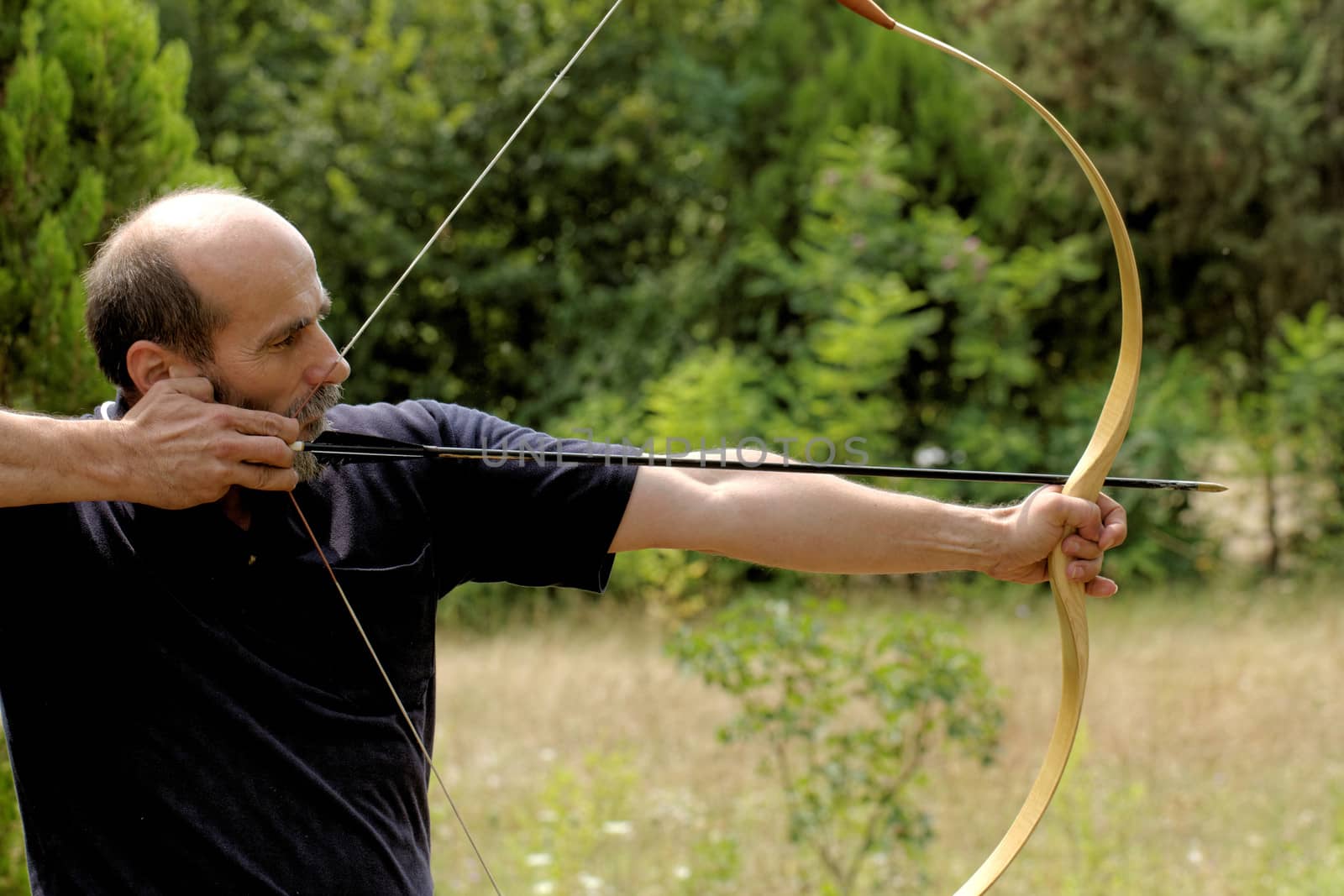 archery man shooting arrow with bow in the nature