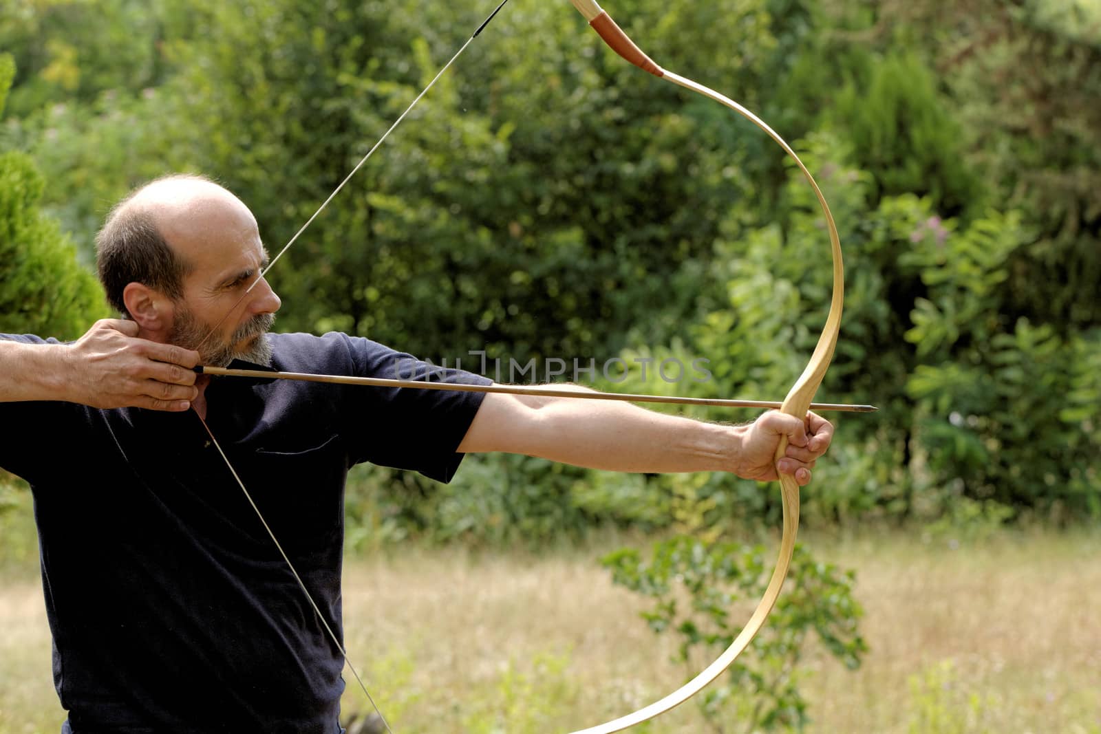 archery man shooting arrow with bow in the nature