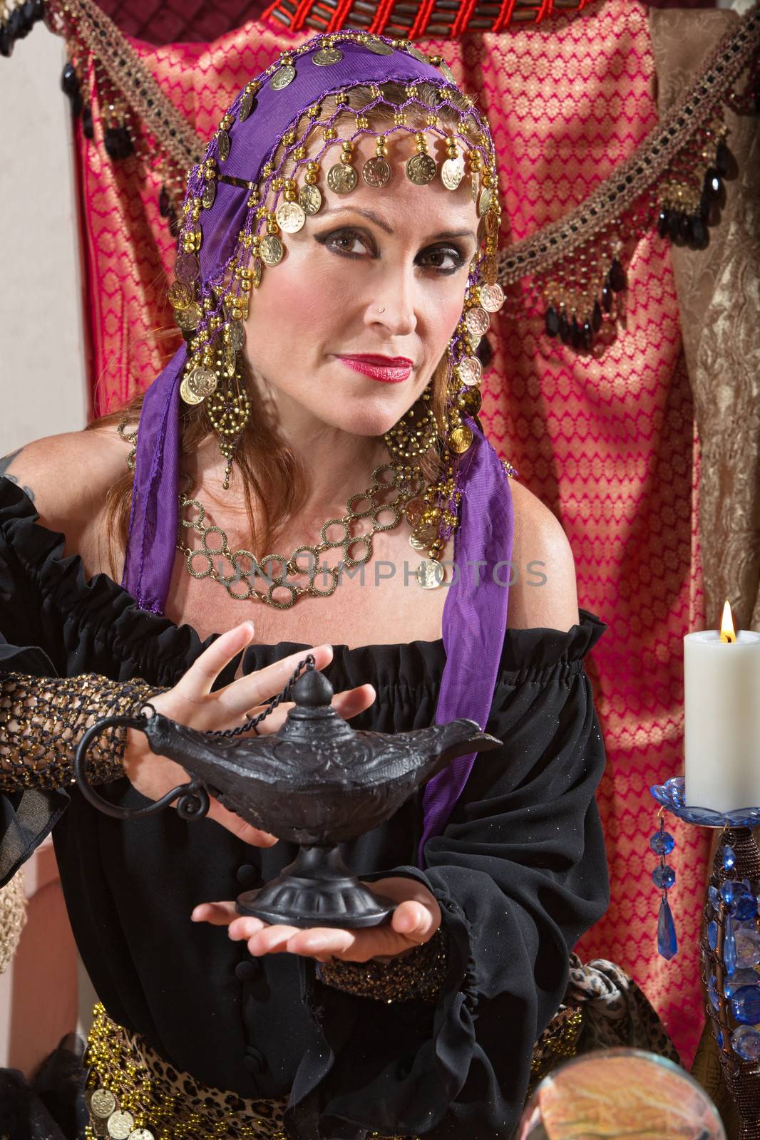Pretty female gypsy fortune teller rubs a magic lamp