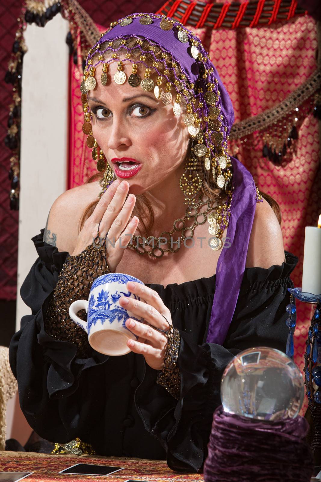 Surprised fortune teller reading tea leaves cup
