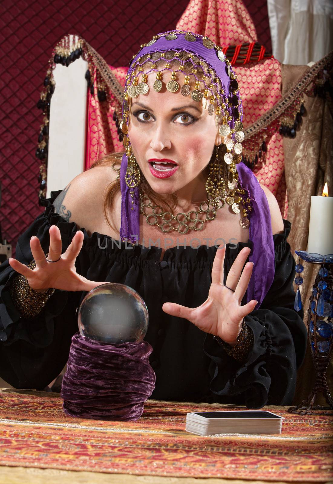 Charming Caucasian woman in headscarf waving hands over crystal ball