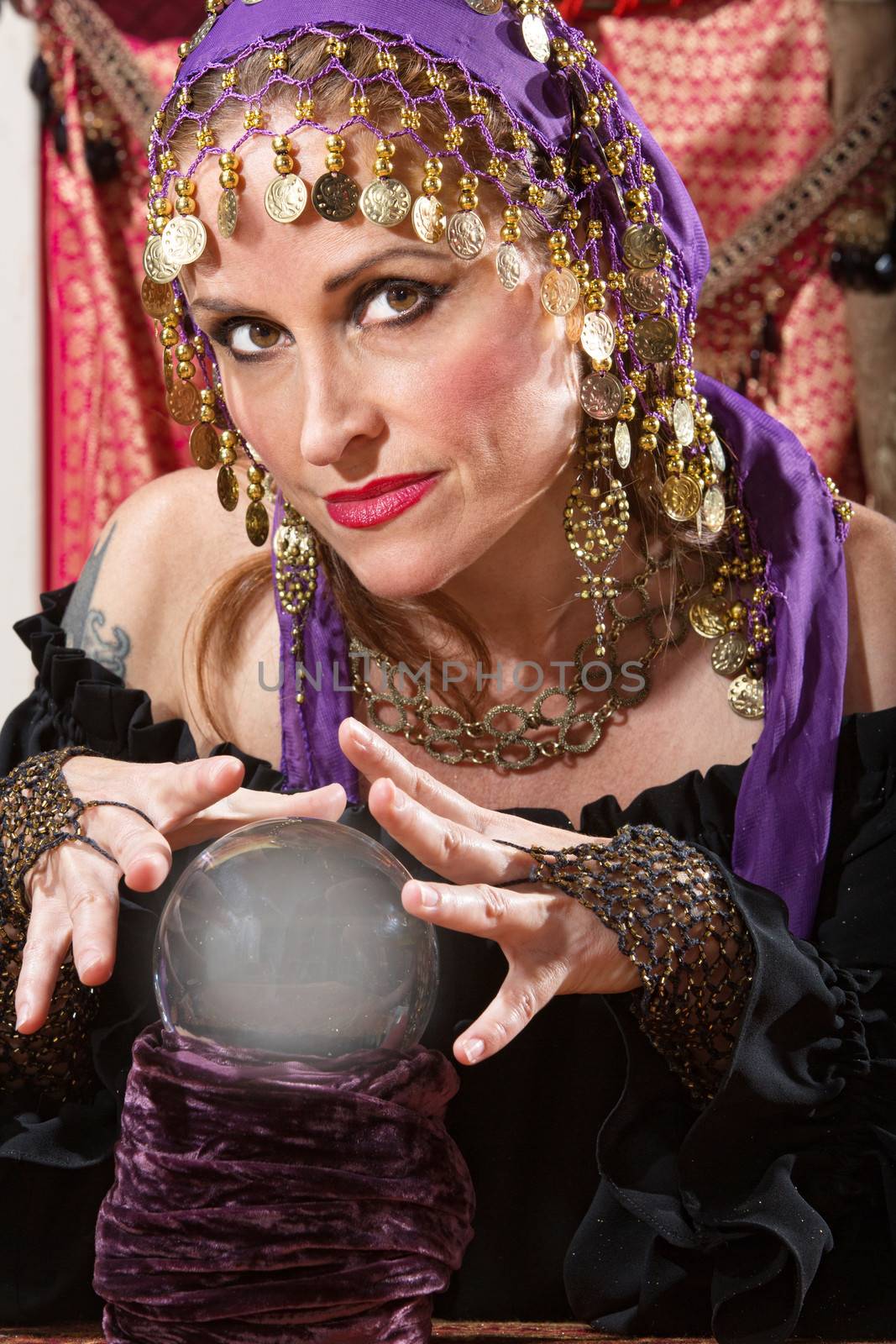 Pretty lady waving hands over crystal ball