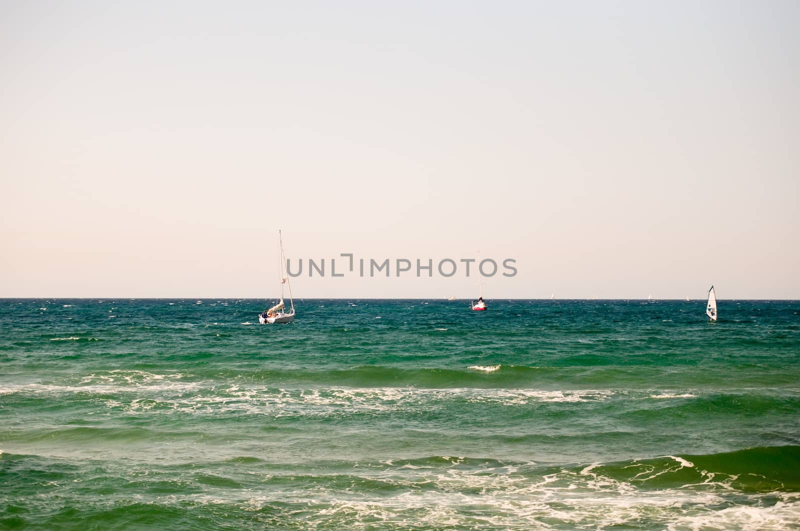 Water sports: windsurfer with bright colored sail . Tel Aviv marina. Israel.