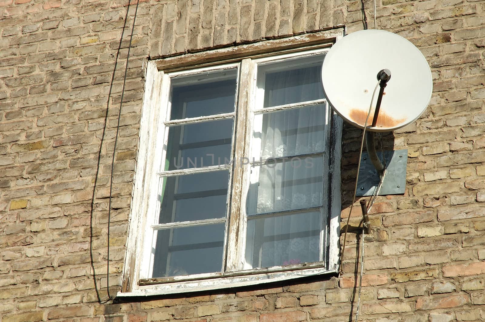 Old white wooden window in brick wall and old satellite dish 