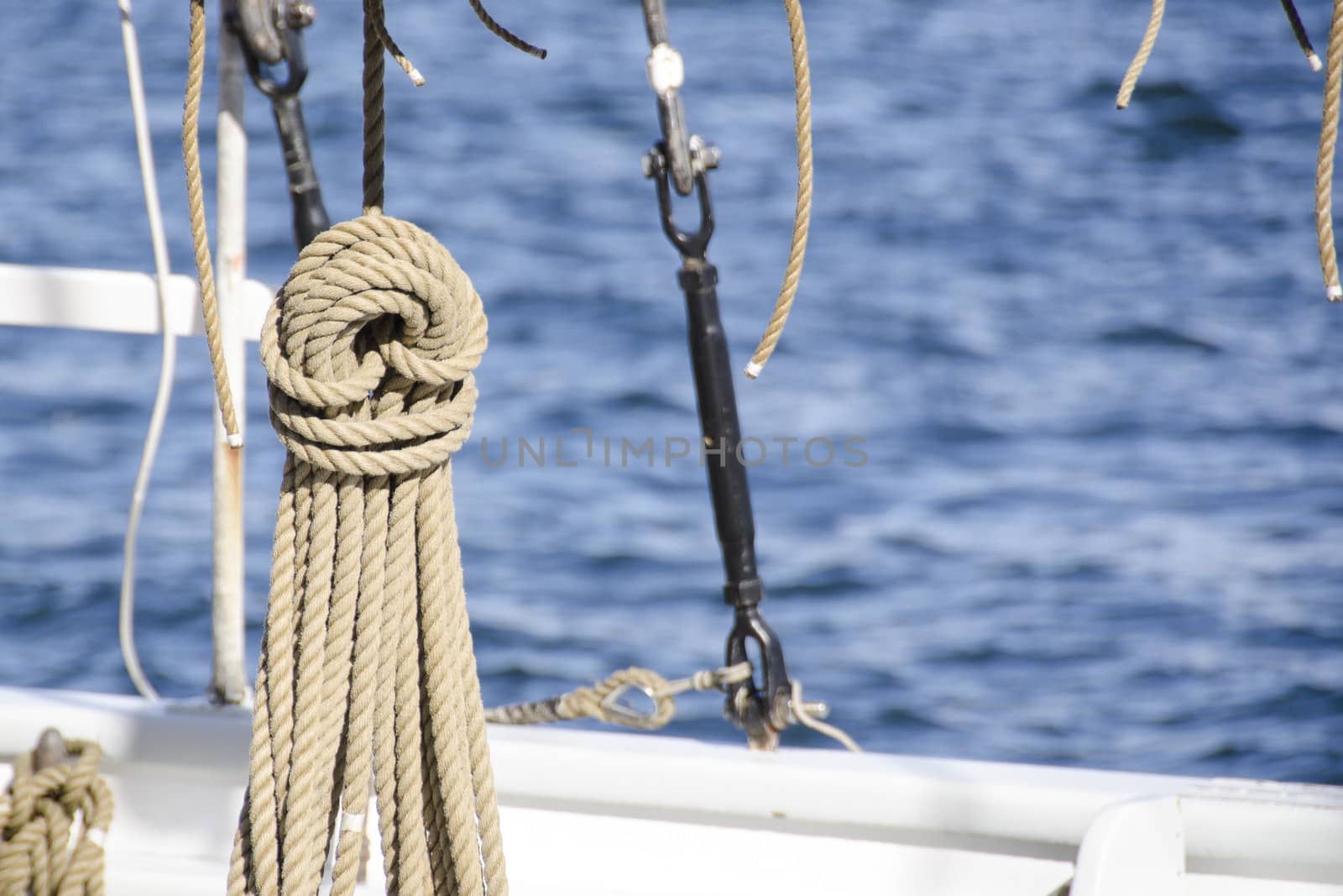 Ropes detail on an old sail ship hanging in front of blue water