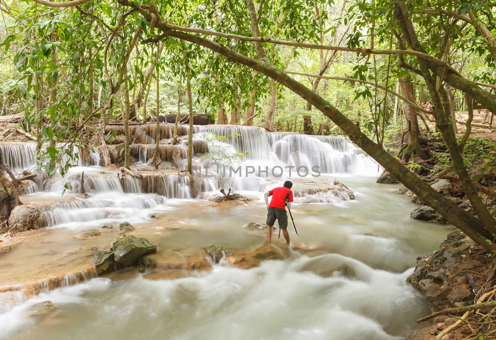 photographer taking picture of waterfall by panyajampatong