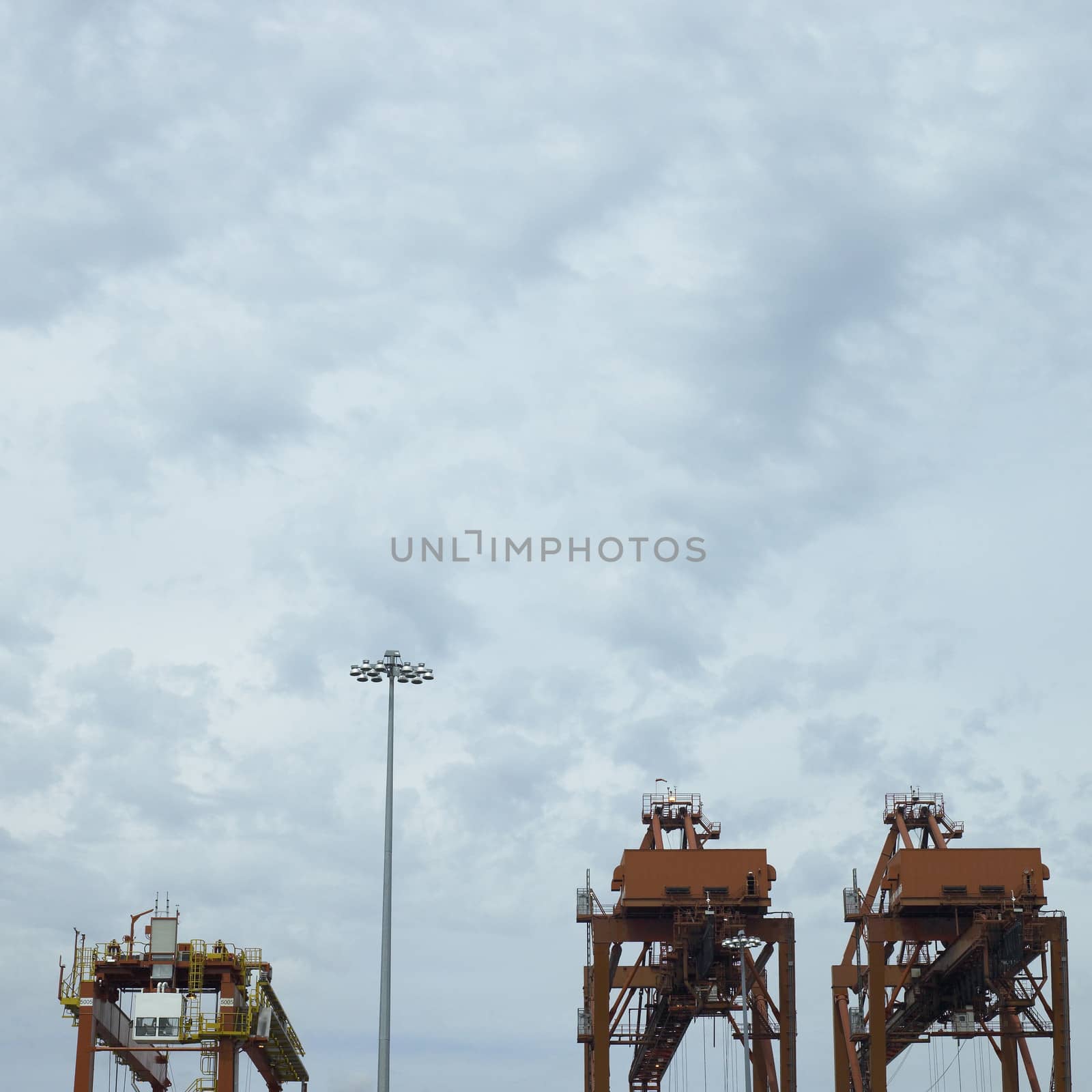 large orange port cranes and cloudy sky