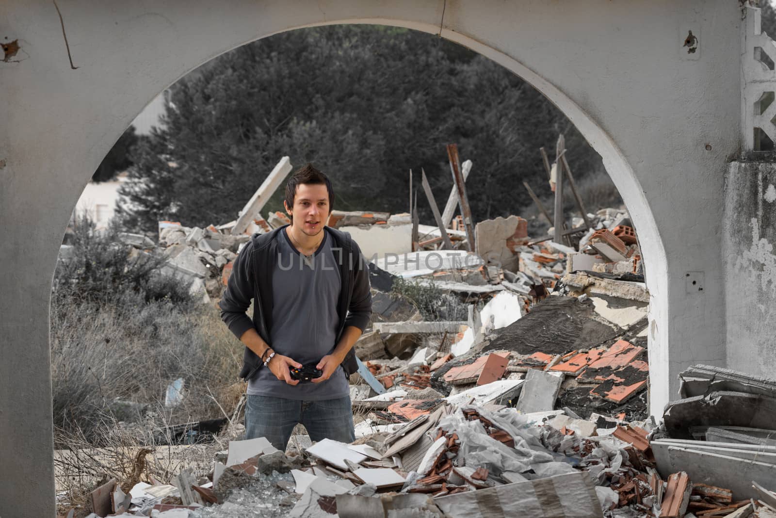 Guy playing with his console surrounded by rubble, a concept