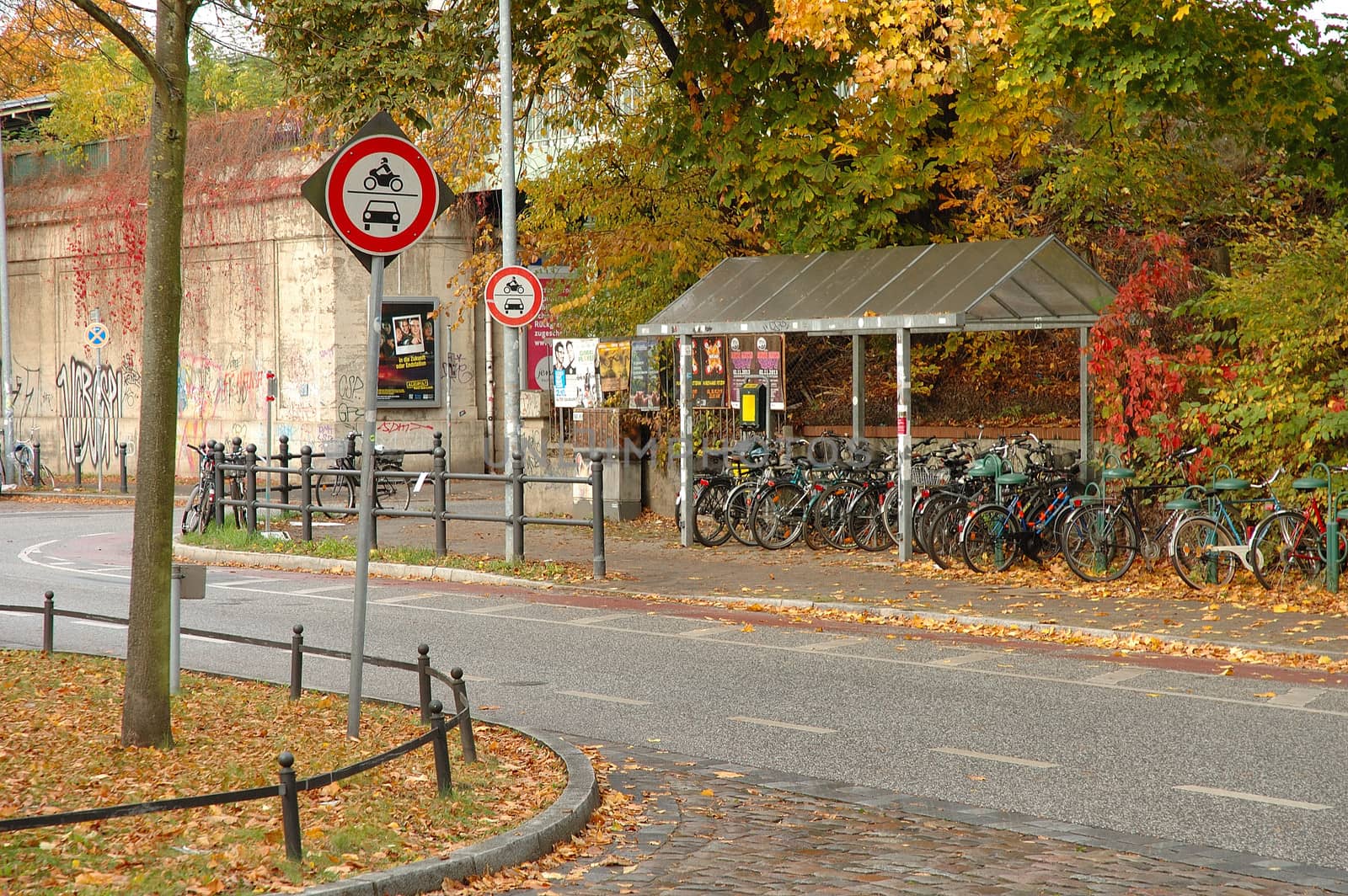 Signs, bicycles and autumn leaves nearby railway station by janhetman