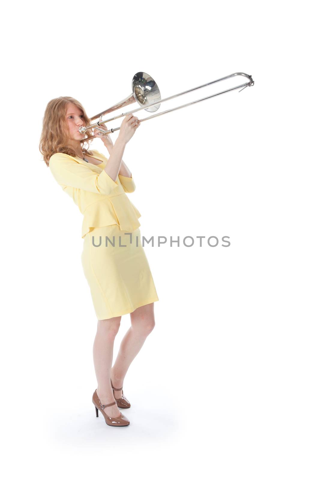 young woman in yellow playing trombone and white background