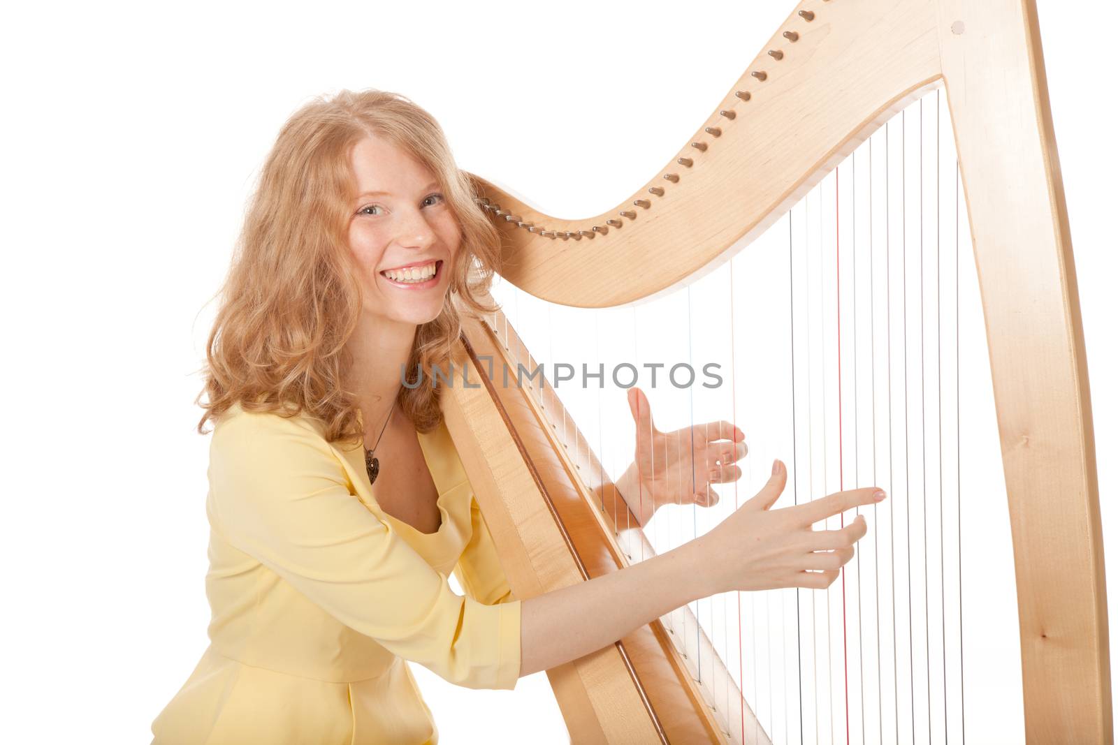 girl in yellow playing the harp against white background