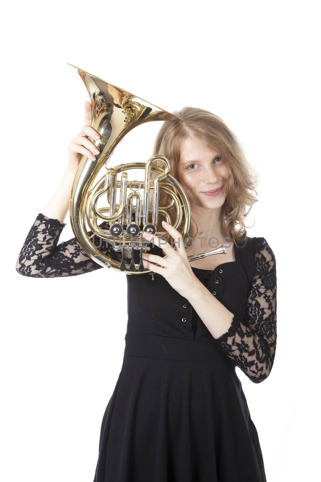 young pretty woman holding french horn against white background