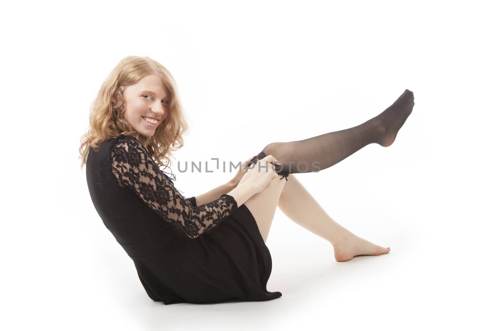 young woman in black putting on stocking against white background