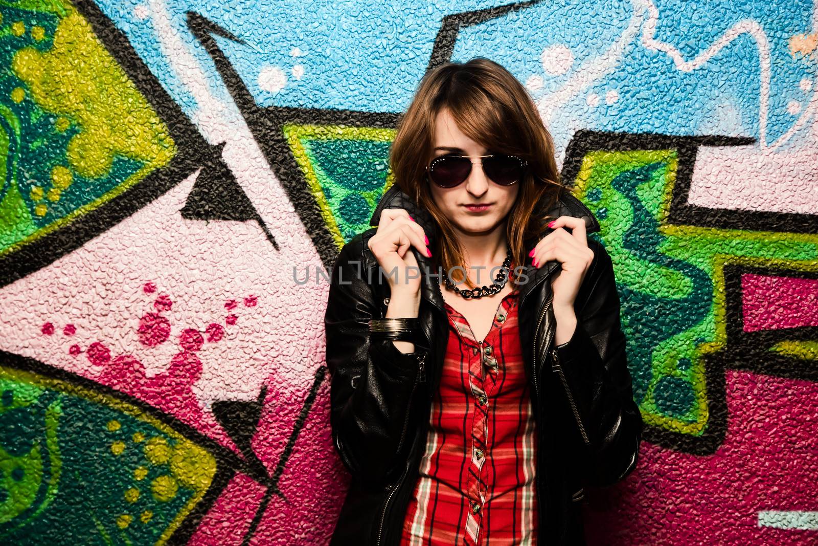 Stylish fashionable girl posing against colorful graffiti wall. Fashion, trends, subculture