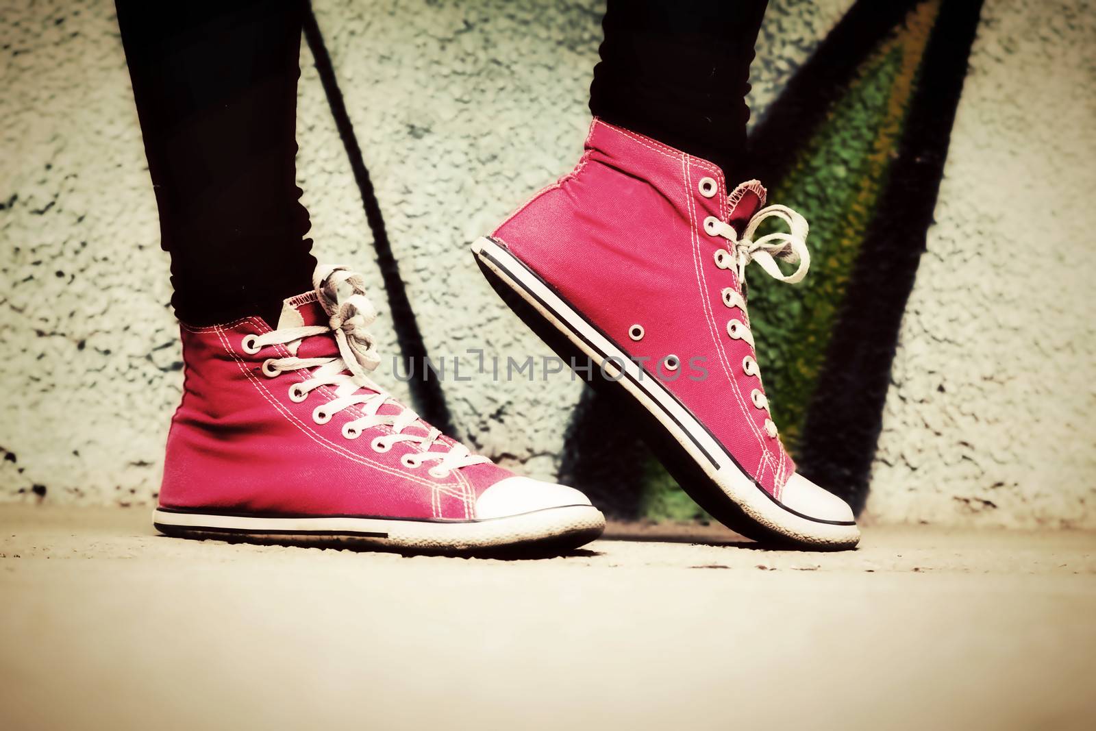 Close up of pink sneakers worn by a teenager. Grunge graffiti wall, retro vintage style
