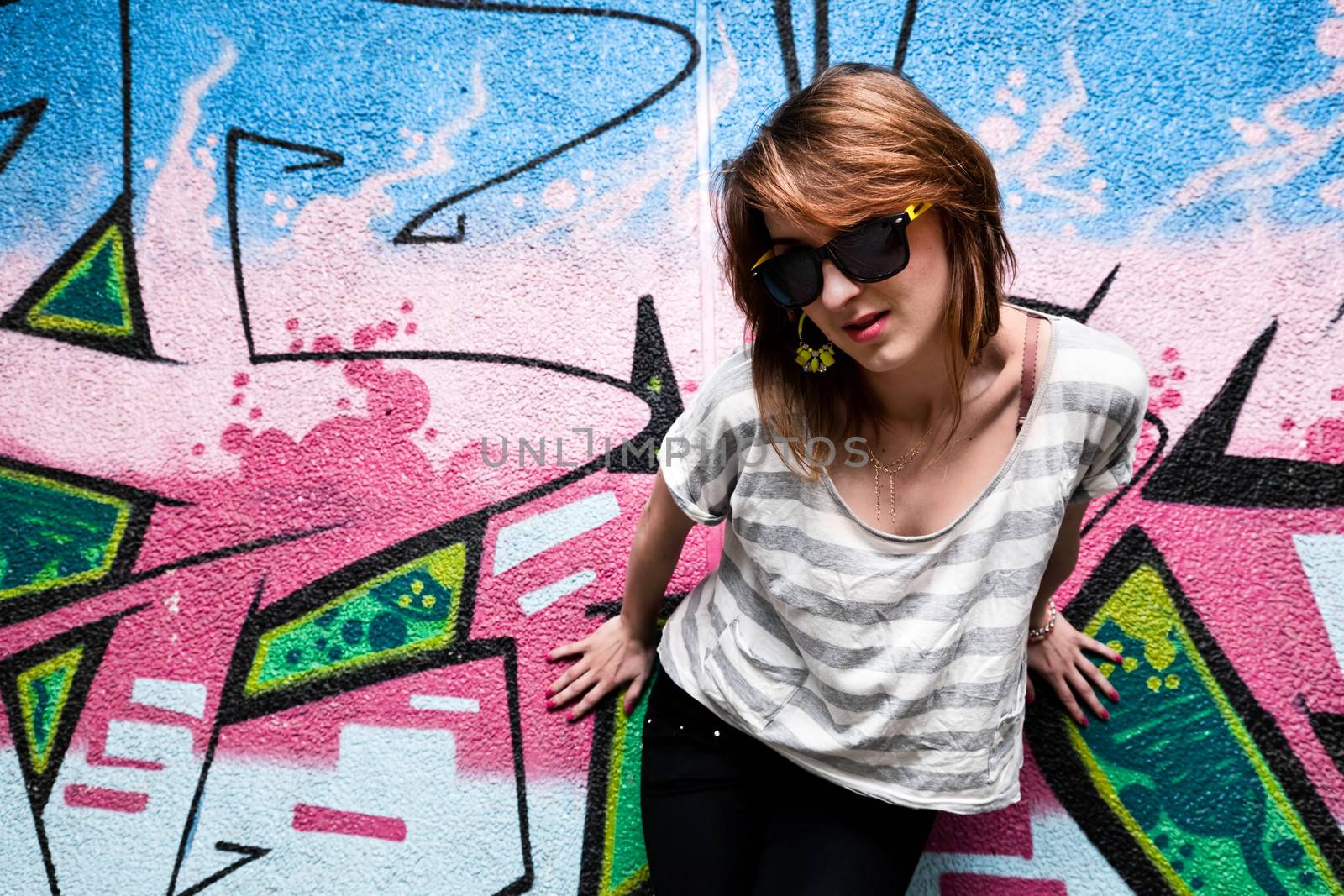 Stylish girl in a dance pose against graffiti wall by photocreo