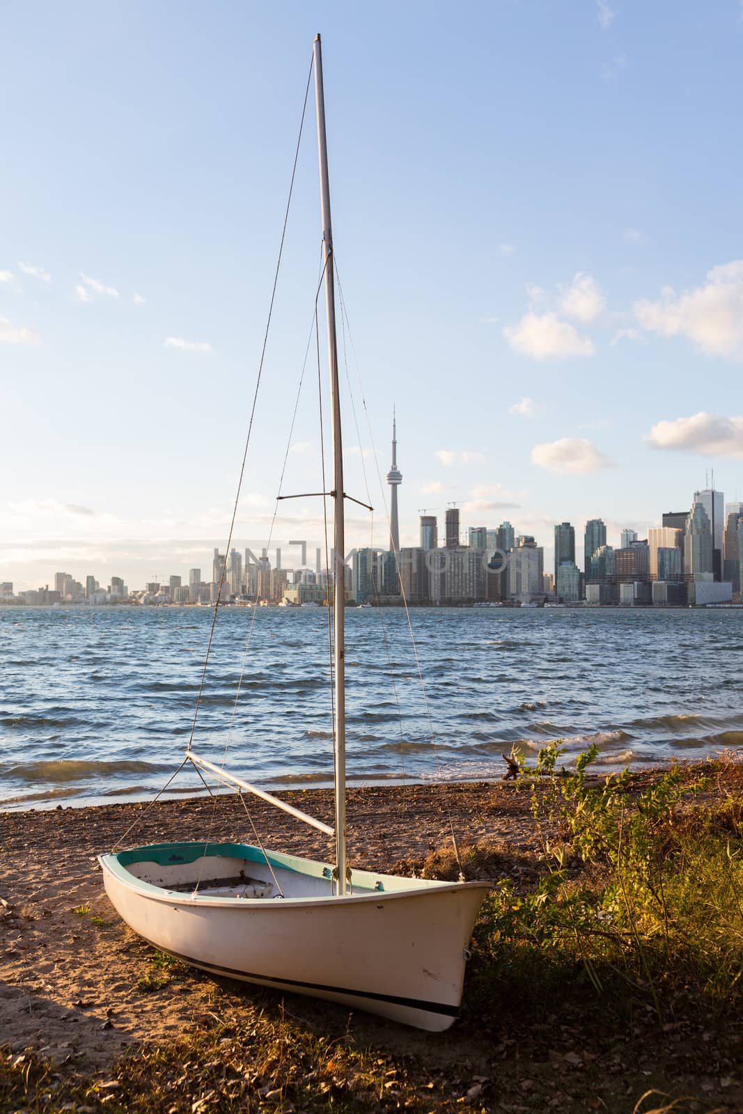 Single sailing boat beached on sandy shore of Lake Ontario on Wade Island of Toronto Islands with skyline of city in the background