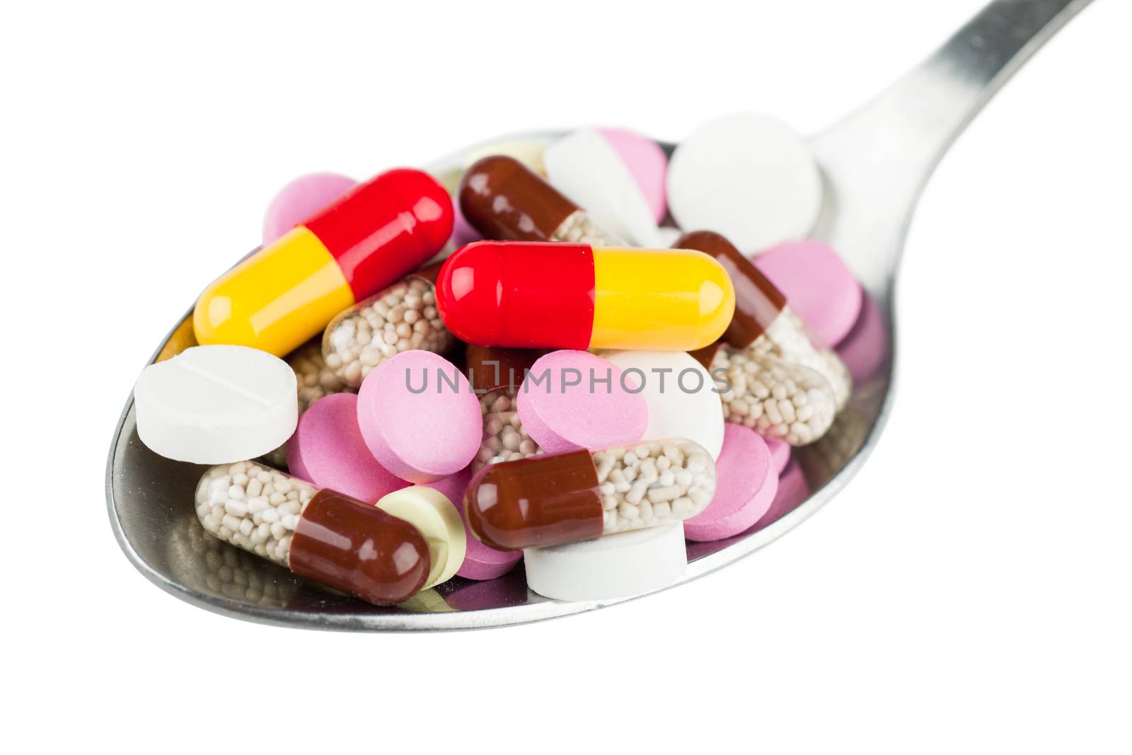 Closeup view of colorful pills in spoon isolated over white background