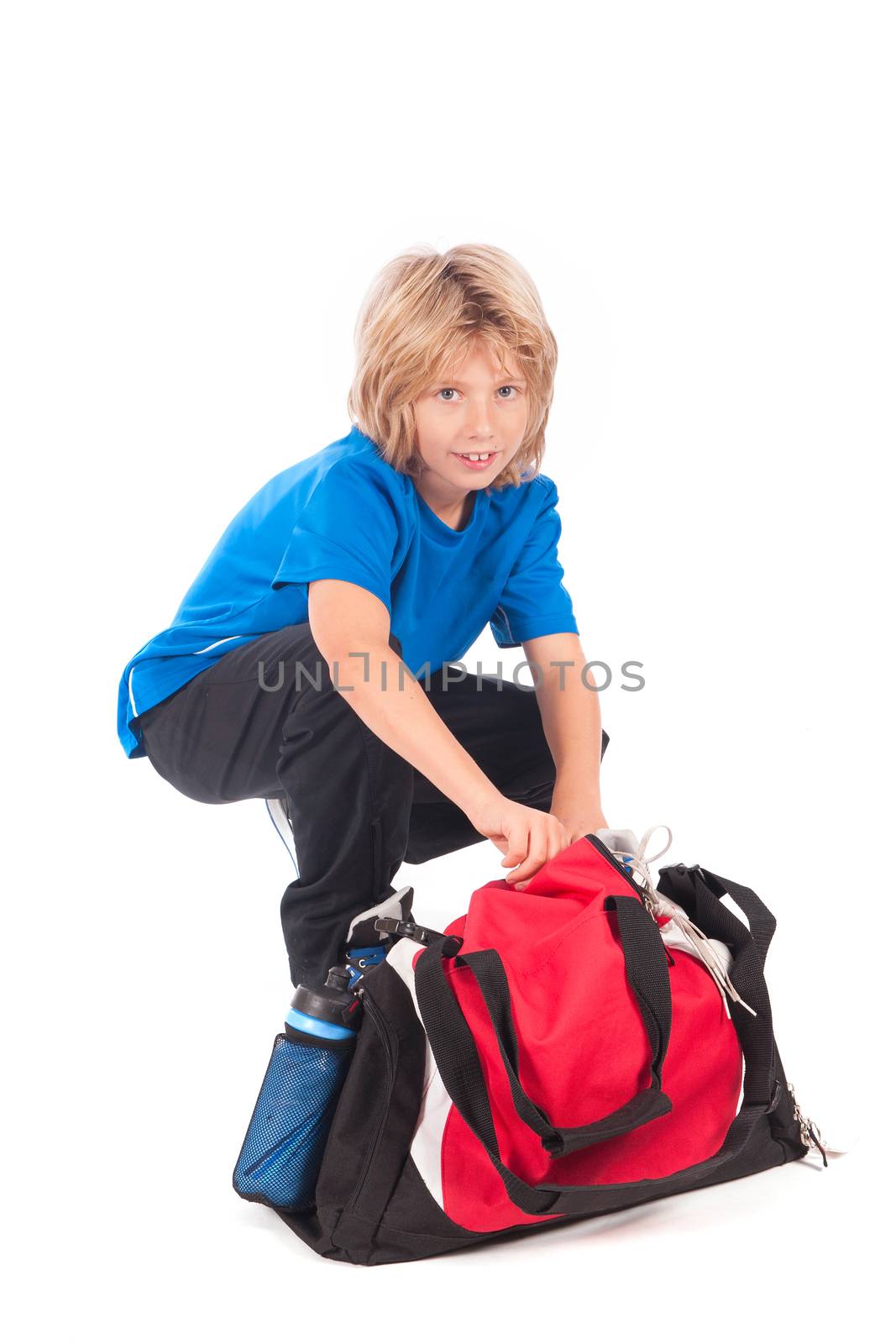 a young boy, ready for going to play football, with his sportbag and football
