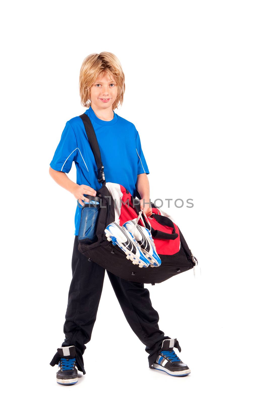 a young boy, ready for going to play football, with his sportbag and football