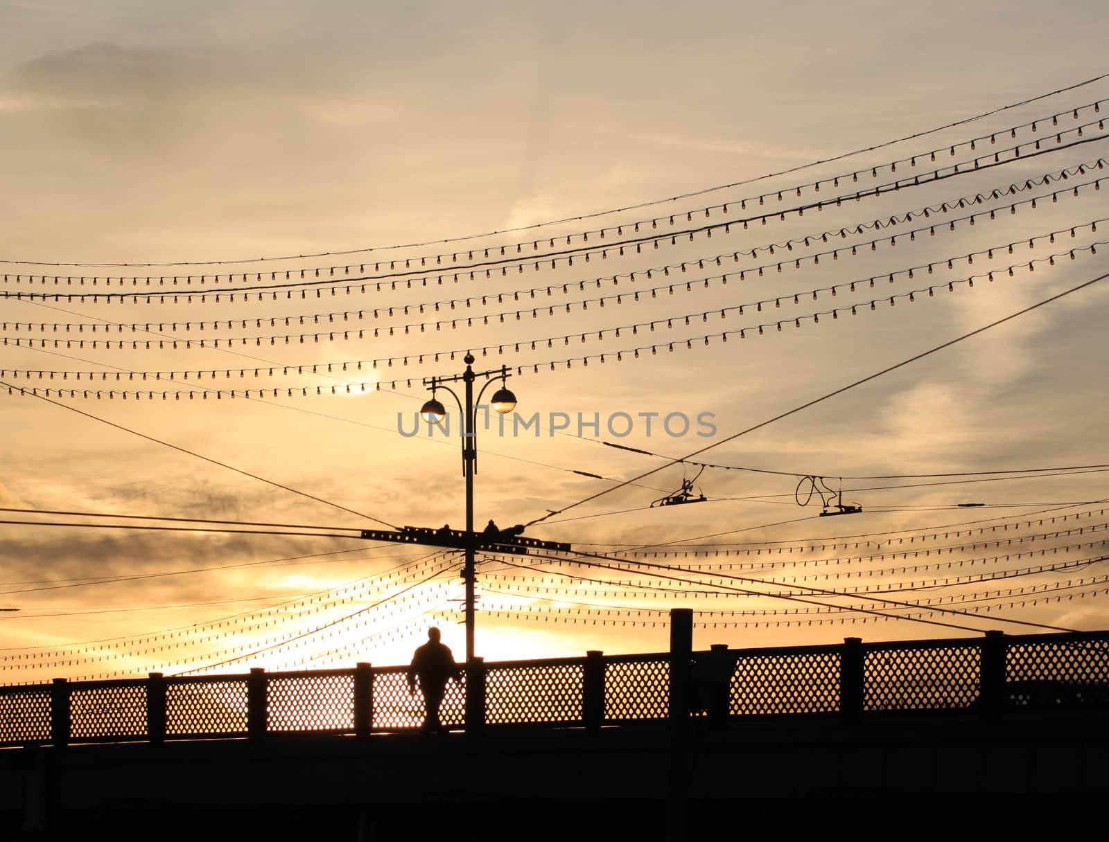 A man walks across the bridge at sunset