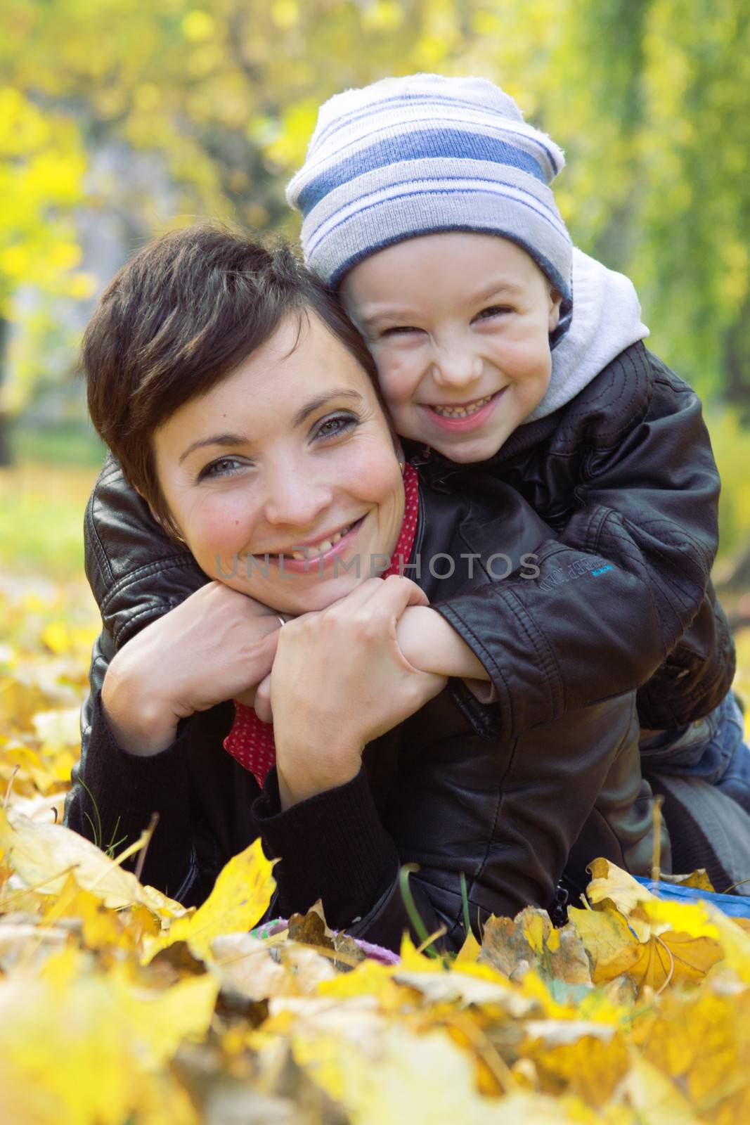 Mother and son lying on autumn leaves by Angel_a