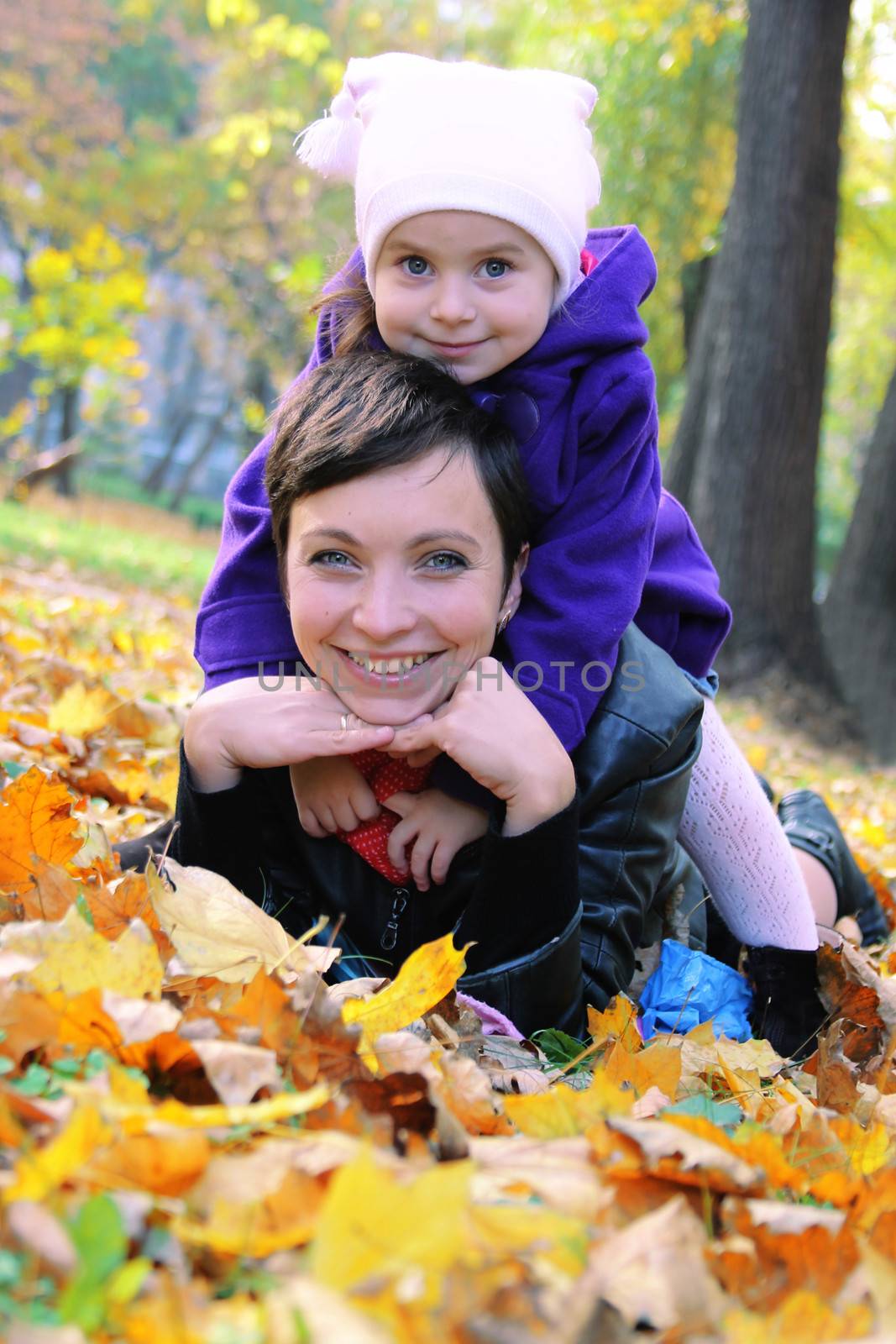 Mother and little daughter lying among autumn leaves by Angel_a