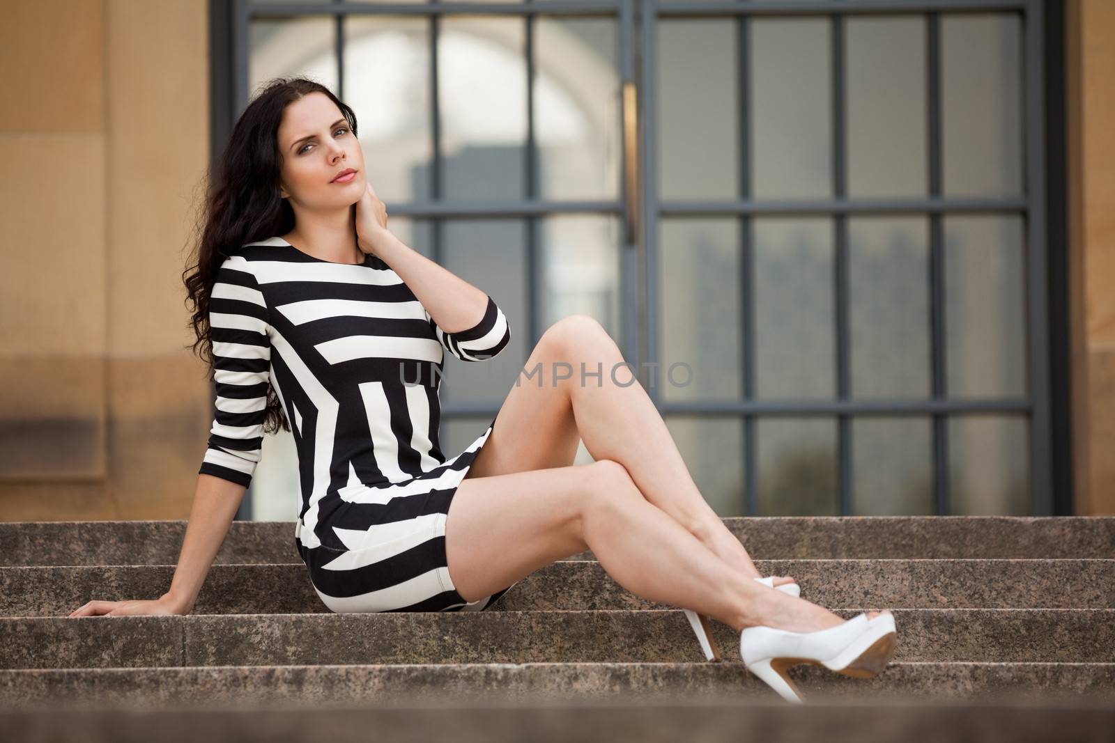 attractive woman in sexy dress in stripes sitting on stairs