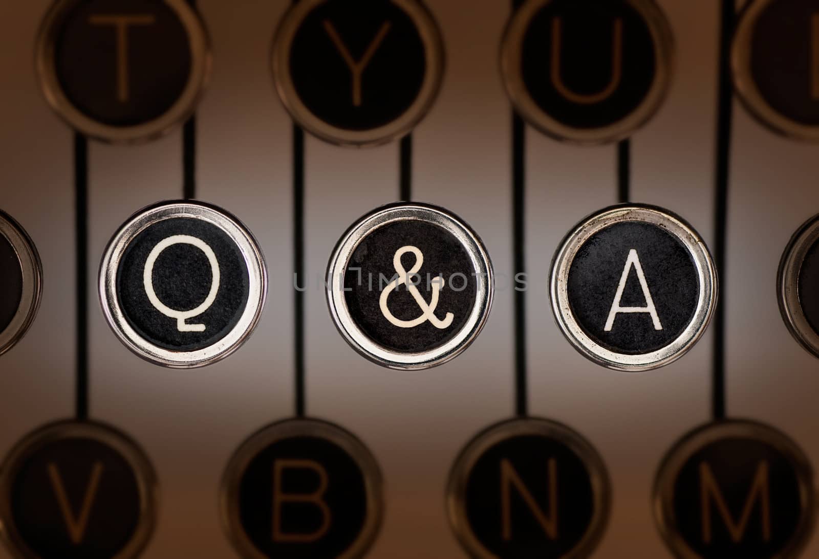 Close up of old manual typewriter keyboard with scratched chrome keys that spell out "Q & A". Lighting and focus are centered on "Q & A" keys. 