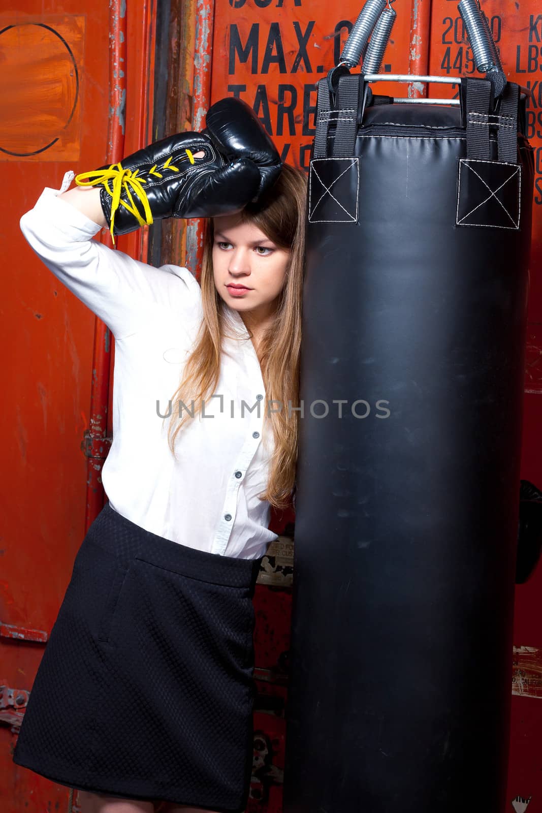 Girl in a business suit near punch bag