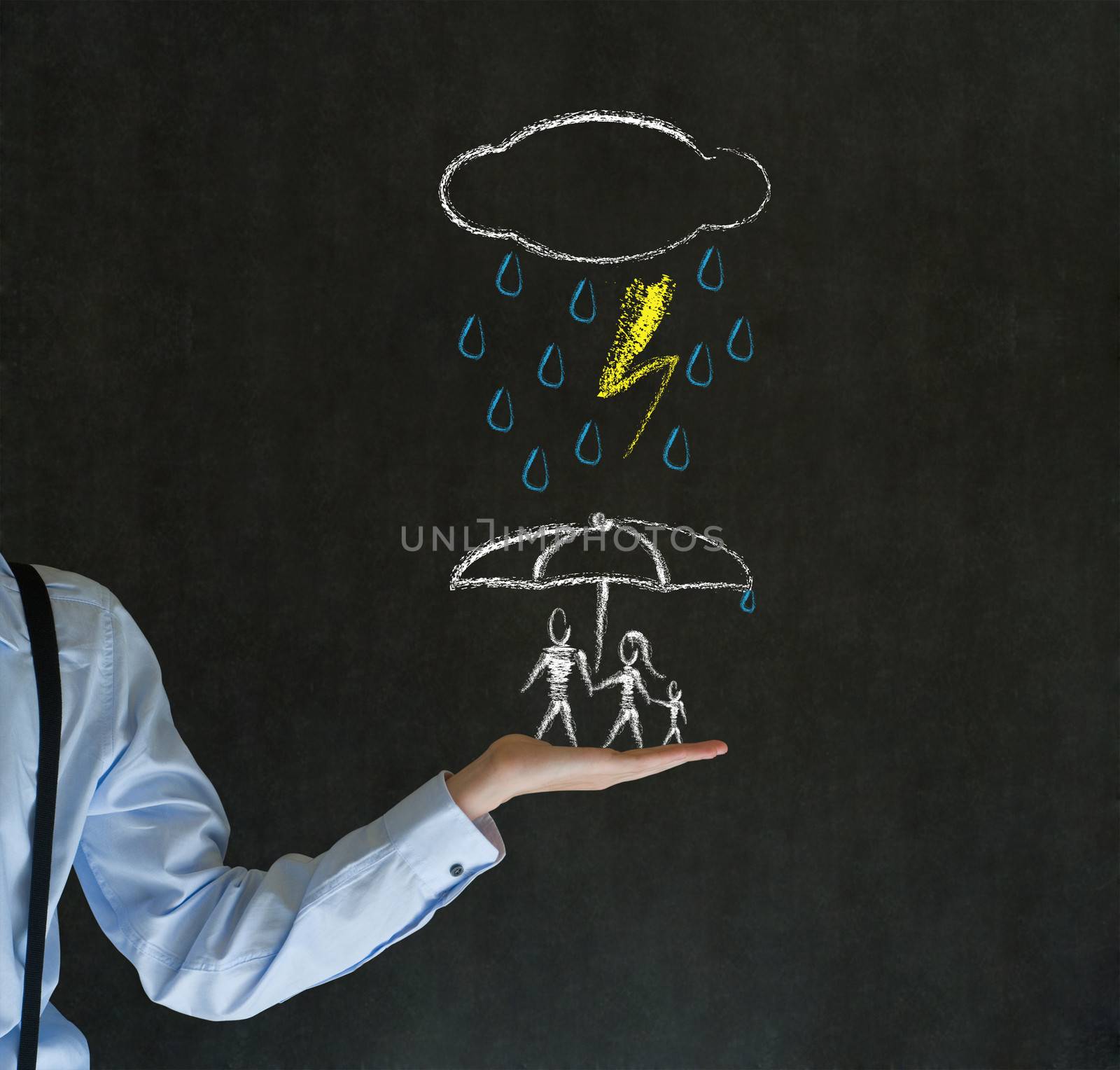 Insurance businessman holding out hand protecting family from natural disaster on blackboard background